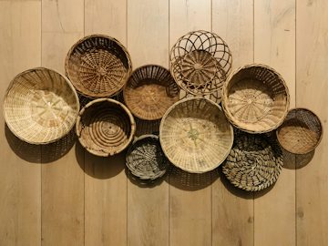 Paniers et corbeilles tissés disposés sur le sol d'un atelier.
